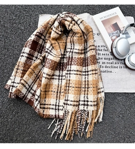 Flat lay of warm checkered scarf with tassels, headphones and book for cozy autumn vibes