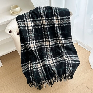 Sciarpa a quadri con nappe in nero e verde su sedia bianca, stile invernale accogliente