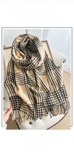 Close-up of classic camel and black plaid scarf featuring fringe edges and soft texture