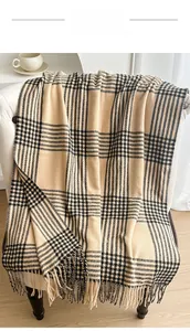 Detail of vintage black and beige plaid scarf with soft fringe on a cozy white chair