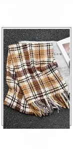 Detail of warm plaid scarf with soft cashmere-like texture and fringed edges in autumn tones