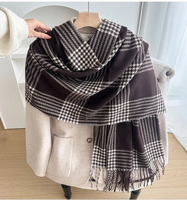 Detail of a thick vintage plaid scarf with tassels on a beige coat in a cozy room