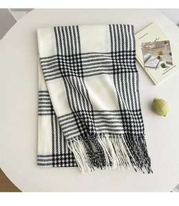 Detail of black and white plaid scarf with fringe on a white table with a magazine