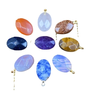 Faceted oval agate stone pendant set with 9 colors and metallic loops on white background