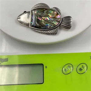 Detailed view of 12g fish brooch made with silver-tone metal and colorful abalone shell inlay
