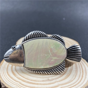 Macro detail of vintage fish brooch featuring iridescent shell inlay on a wood base