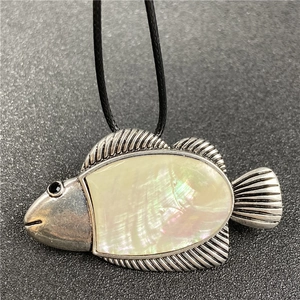 Macro shot of silver fish pendant featuring iridescent shell inlay and engraved details