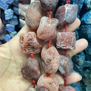 Gros plan de perles d'agate rouge brute avec texture naturelle sur cordon rouge