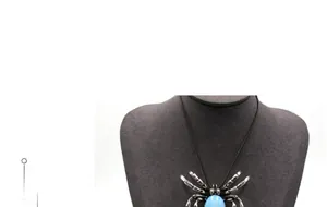 Vue macro du collier araignée argenté avec gemme bleue sur un mannequin de cou noir