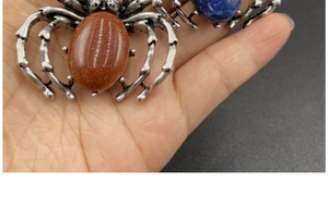 Gros plan d'une broche araignée vintage avec pierre bleue ovale et pattes métalliques