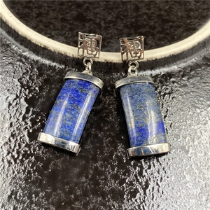 Makro-Detail von blauen Lapislazuli-Ohrringen mit silbernem Fu-Zeichen-Stecker
