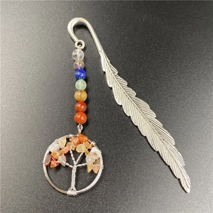 Macro detail of silver metal feather bookmark with colorful chakra stones and tree of life