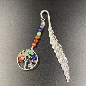 Macro detail of silver feather bookmark with colorful chakra stones and Tree of Life pendant