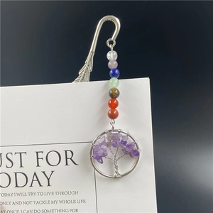 Macro detail of silver feather bookmark with seven chakra beads and tree of life pendant