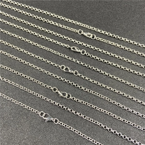 Detailed macro view of silver copper O-chain necklaces with lobster clasps on black surface
