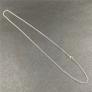 Detail of silver O-shaped copper chain with lobster clasp on dark textured surface