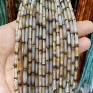 Macro shot of 3x12mm natural silk agate cylinder beads with unique brown striped patterns