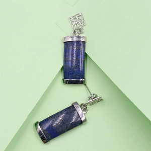 Lapis Lazuli Ohrhänger mit silbernen Metallkappen auf grünem Hintergrund
