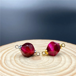 Macro shot of rose red tiger eye stone connectors with gold and silver loops on wood