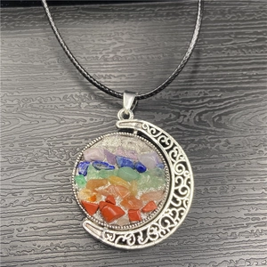 Detailed shot of rotating sun and moon pendant with colorful natural seven chakra stones