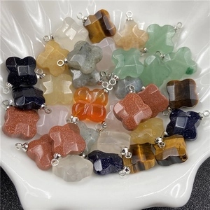 Detailed view of assorted natural crystal four-leaf clover pendants in a shell bowl