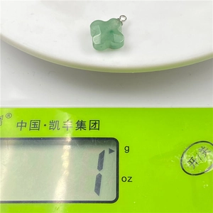 Weight measurement of a green jade four-leaf flower pendant on a scale, 1g precision