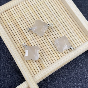 Macro detail of rose quartz clover pendants with silver loops on a bamboo tray
