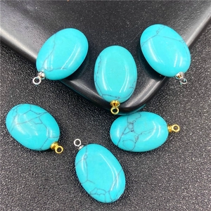 Macro-detail van ovale turquoise hangers van turquoise met zwarte textuur en goud en zilveren bails