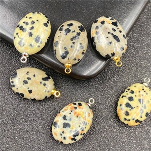 Macro detail van ovale dalmatiër jaspis stenen hangers met goud- en zilverkleurige oogjes