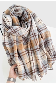 Close-up of thick plaid scarf featuring soft fringe and warm autumn color texture