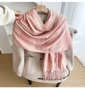 Detail of pink and white checkered scarf with fringe tassels on a wooden rack
