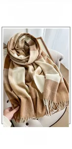 Detailed view of soft cashmere feel fabric and tassels on a classic plaid pattern scarf
