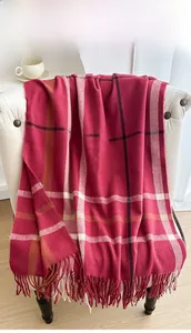 Detailed view of red plaid tassel scarf draped on a chair for a warm winter aesthetic