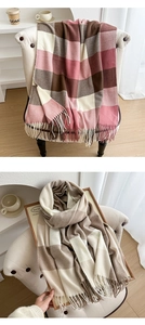 Close-up of soft plaid scarves with tassels in pink and beige on a stylish white chair