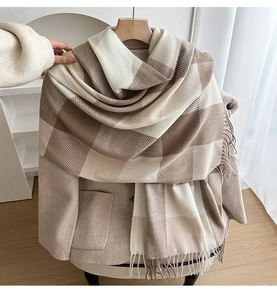 Close-up of soft brown and white checkered scarf with fringe tassels on a coat hanger