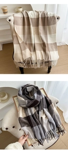Detail of plaid tasseled scarves in beige and black-grey knit on a wooden tray
