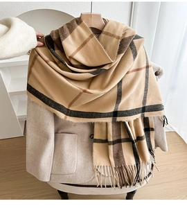 Macro detail of khaki plaid tassel scarf fabric texture against beige wool coat