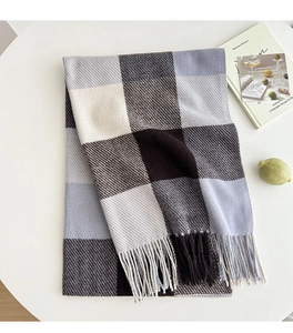 Detailed view of the soft plaid scarf texture and fringe edges on a white table