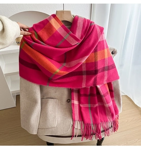 Detail of pink plaid scarf with thick tassels layered on a beige blazer jacket