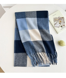 Detailed view of blue and white plaid scarf with soft knit texture and fringe edge