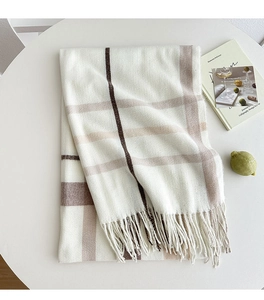 Detailed view of checkered beige and brown winter scarf with tassels on a white table
