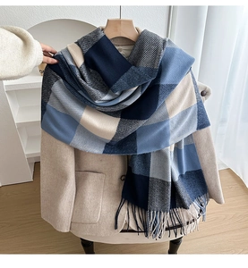 Detail of classic plaid scarf with blue and beige tassels draped over a beige suit