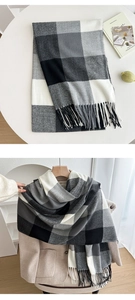Detail of soft black, white and grey checkered scarf with fringe on a white table