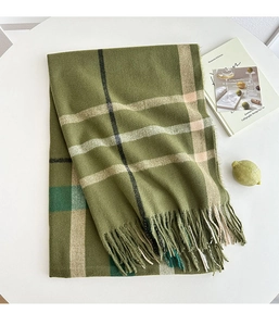 Detail of dark green plaid scarf with long fringe texture on a white table set