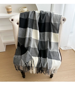 Close-up detail of soft plaid scarf with fringe on a cozy armchair in home setting