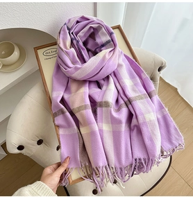 Detail of purple plaid tassel scarf on a wooden tray for a cozy winter atmosphere
