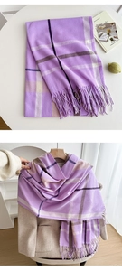 Detailed view of soft purple plaid scarf with fringe on a beige coat and white table
