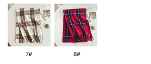Detailed view of checkered scarves with fringe edges in beige, brown and red plaid