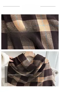 Macro detail of thick plaid scarf fabric texture featuring fringe edges and warm colors