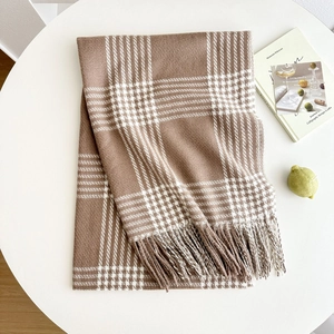 Classic brown and white plaid winter scarf with fringe on a white decorative table
